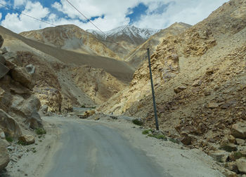 Road leading towards mountains against sky