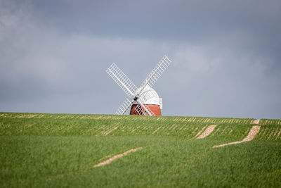 Traditional windmill on field against sky