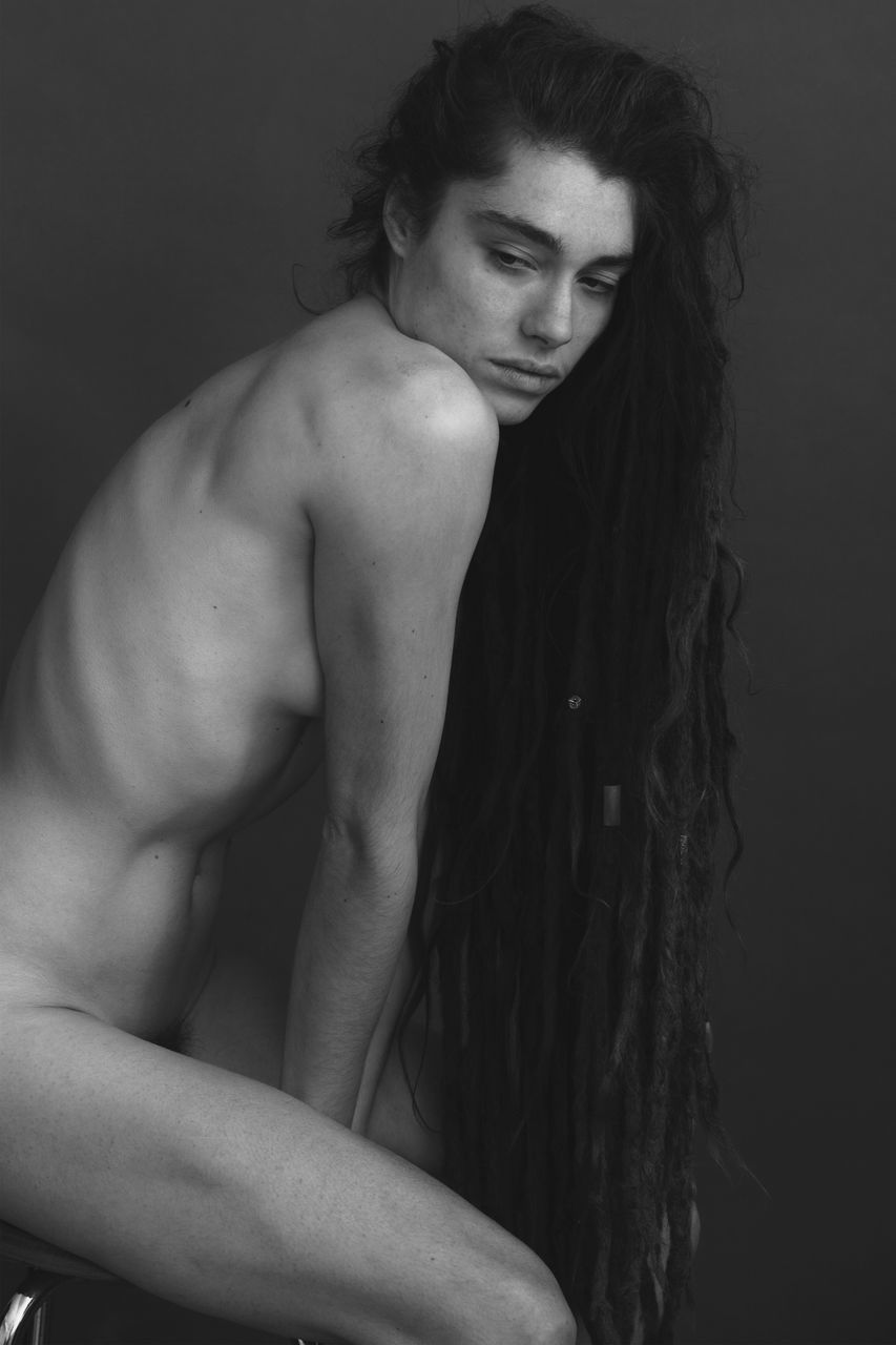 black and white, one person, young adult, adult, hairstyle, muscular build, portrait, monochrome photography, long hair, studio shot, lifestyles, indoors, person, monochrome, strength, black, looking at camera, photo shoot, fashion, waist up, women, human face, three quarter length, arm, men, black background, clothing, human hair, looking, wellbeing