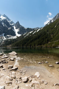 Scenic view of lake by snowcapped mountains against sky