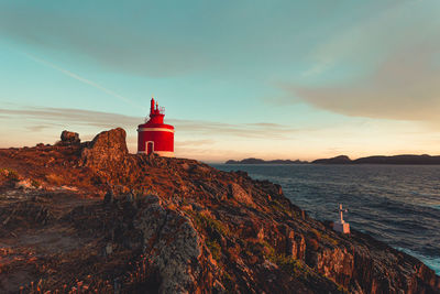 Lighthouse by sea against sky