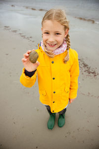 Full length portrait of girl holding stone while standing at beach