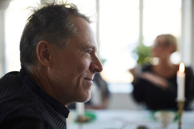 Side view of smiling mature man looking away at home