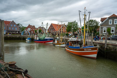 Boats moored in canal amidst buildings in city