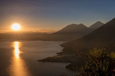 Scenic view of lake and mountain against sky during sunset