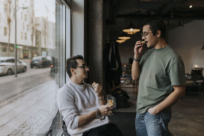 Young male entrepreneurs having cookies during break time at creative workplace