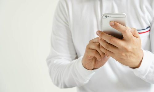 Midsection of man using mobile phone against white background