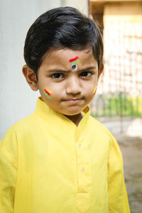 Portrait of cute boy wearing yellow traditional clothing outside house