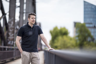 Handsome young man standing on bridge