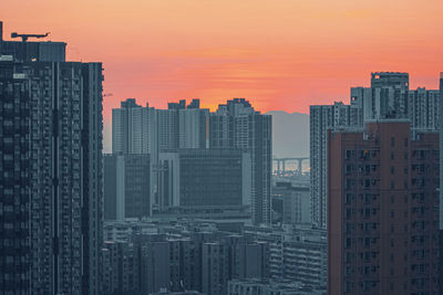 Modern buildings in city against orange sky