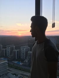 Man looking through window at sunset