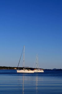 Sailboat on sea against clear blue sky