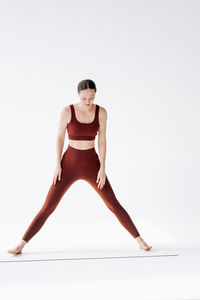 Portrait of young woman exercising against white background