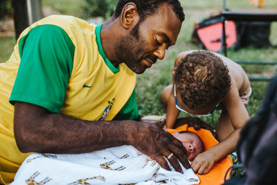 Black father relaxes with his two sons outdoors