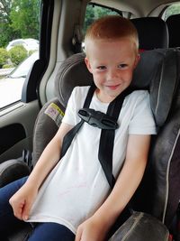 Cute boy sitting in his car seat, showing his juice stained t-shirt 