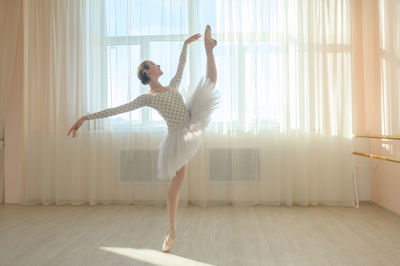 Full length of young woman exercising at home