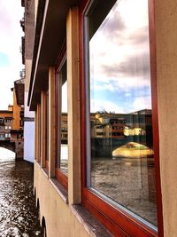 Bridge over river by buildings in city against sky