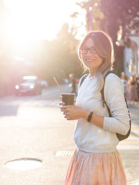 Portrait of smiling young woman standing on road