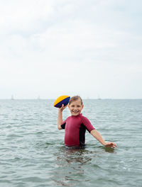 Portrait of smiling girl in sea against sky