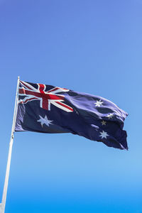 Low angle view of flag against clear blue sky