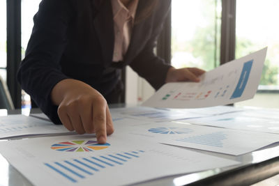 Midsection of woman holding paper with text on table