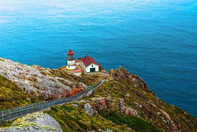 High angle view of lighthouse by sea against buildings