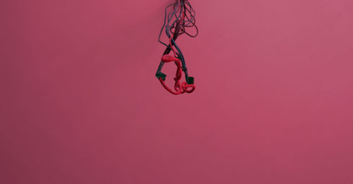 Low angle view of pink hanging against red background