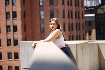 Portrait of woman standing against brick wall