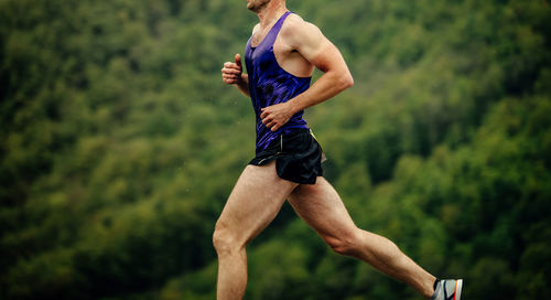 Full length of young man exercising against sky