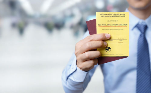 Midsection of man holding documents while standing outdoors