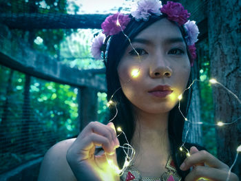 Close-up portrait of young woman holding fairy lights