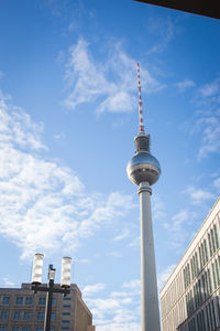 Low angle view of communications tower against cloudy sky