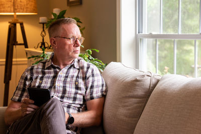 Midsection of man using phone while sitting on sofa at home