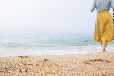 Woman standing on beach against sky