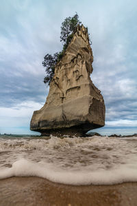 Rock formation on beach against sky