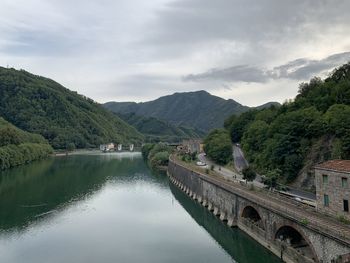 Bridge over river by mountains against sky