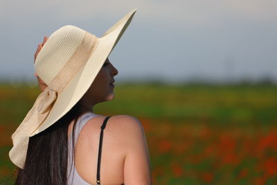 Rear view of woman wearing hat standing on field