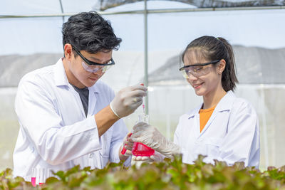 Smiling scientists performing experiment in greenhouse