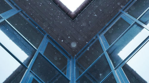 Low angle view of raindrops on glass window