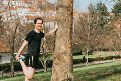 Portrait of man standing by tree against sky