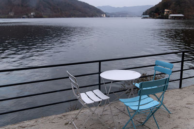 Empty chairs and table by lake