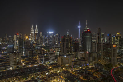 Illuminated modern buildings in city against sky at night