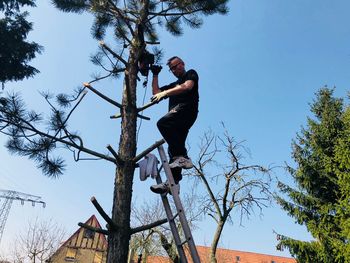 Low angle view of man sitting on plant against sky