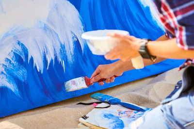 Female artist working on abstract acrylic painting, hand holding paint brush and painting