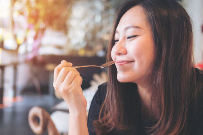 Close-up of smiling holding spoon in restaurant