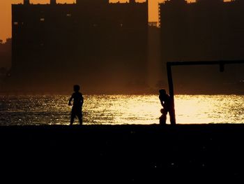 Silhouette people in water at sunset