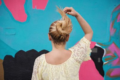 Rear view of woman with hair bun standing against wall