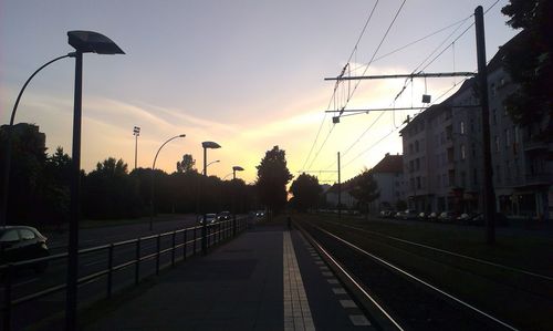 Road passing through city at sunset