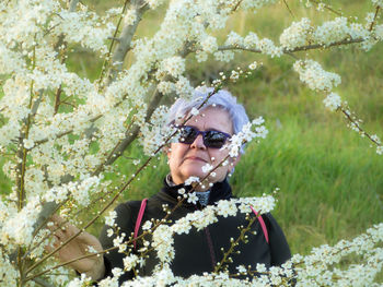 Portrait of senior woman standing by flowers blooming in park