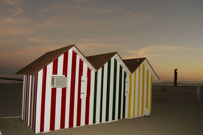 Multi colored huts at beach against sky during sunset